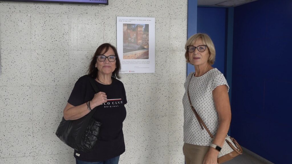 Dues participants del projecte Foto-veu al costat d’una de les fotografies exposades al CAP Sant Pere
