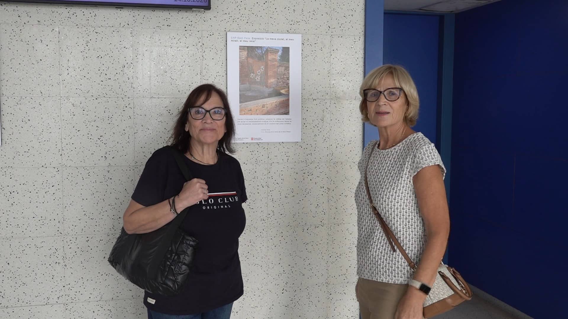 Dues participants del projecte Foto-veu al costat d’una de les fotografies exposades al CAP Sant Pere