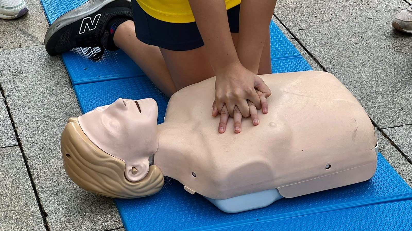 Un infant practica compressions toràciques sobre un maniquí a la plaça de la Llibertat