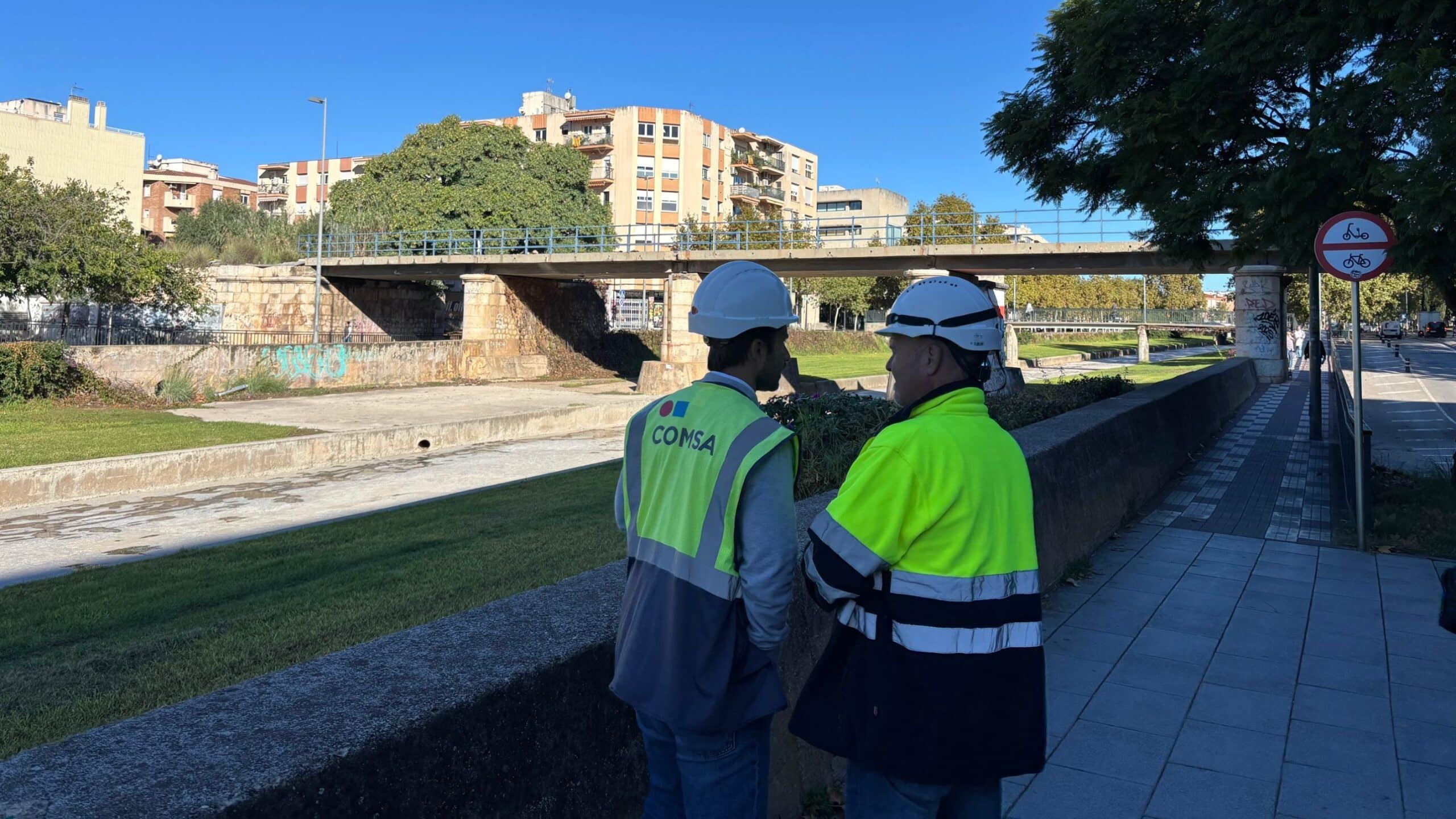 Dos operaris observen el pont de la riera d’Alforja de Cambrils, que serà enderrocat per les obres del tramvia