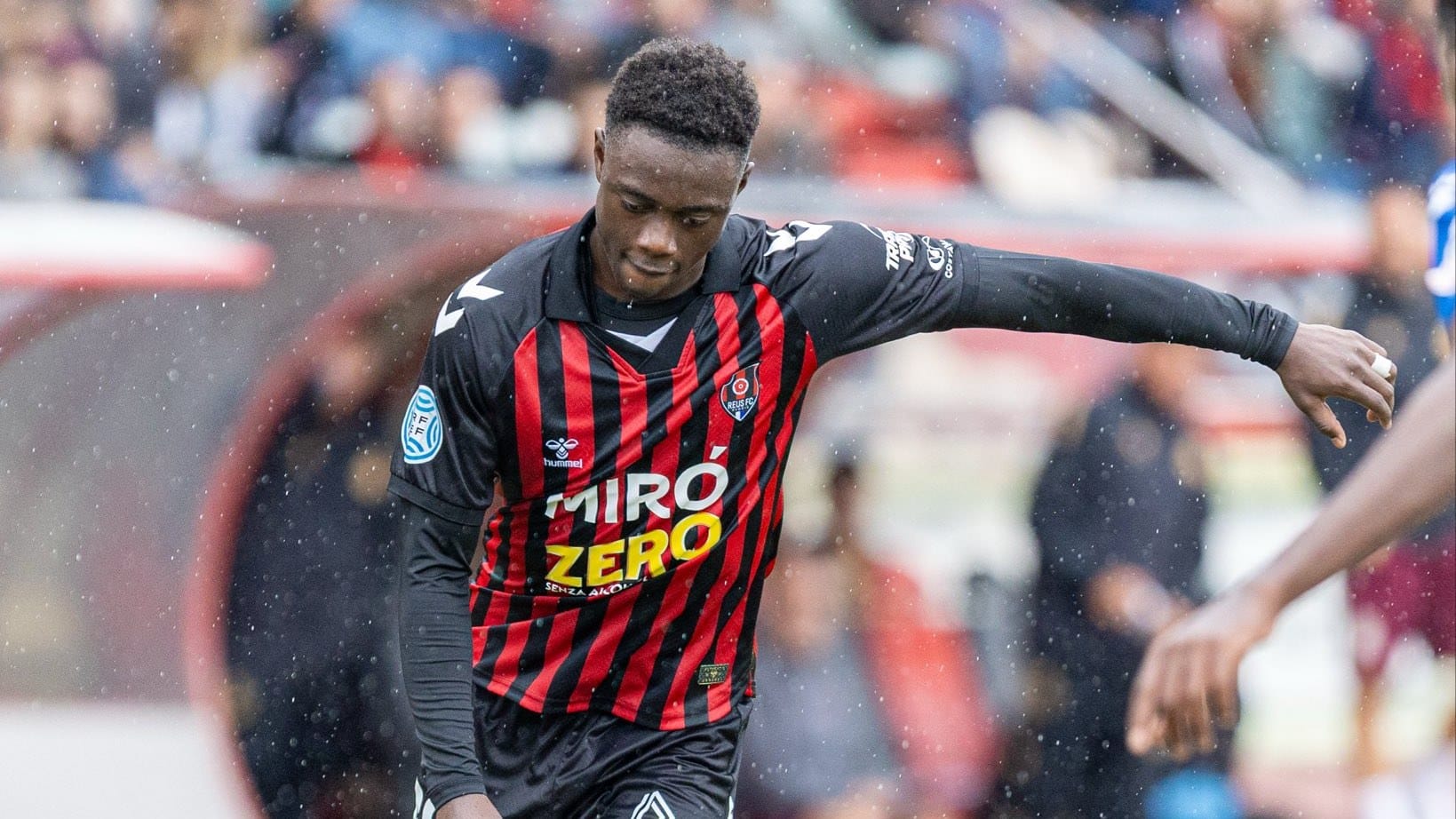 Un jugador del Reus FC Reddis condueix la pilota sota la pluja a l’Estadi Municipal