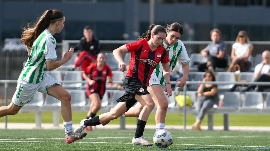 Una jugadora del Reus Femení condueix la pilota davant dues rivals del Fontsanta-Fatjó