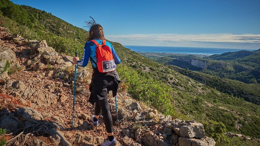 Una participant de la Vandekames baixa per un corriol de muntanya amb vistes al mar
